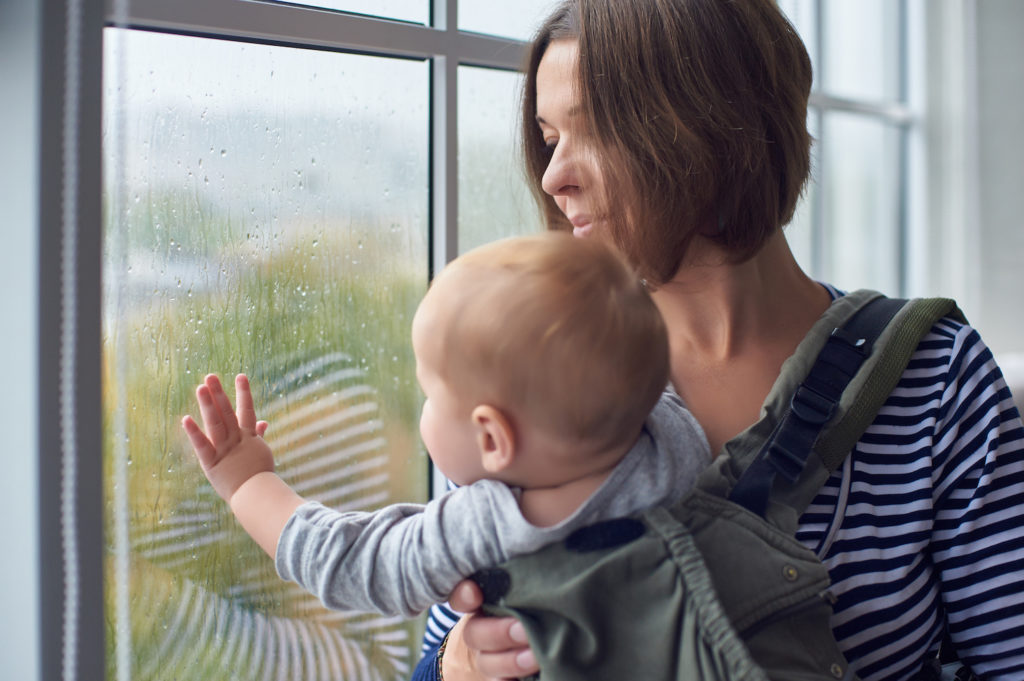 mother and baby looking out of window protected by residential gutters