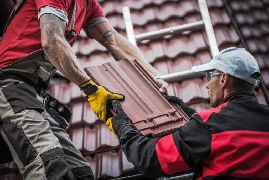 two roofers passing roof tiles