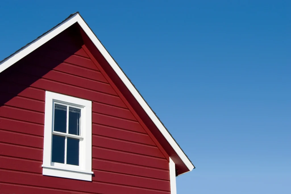 Close up view of barn red vinyl siding color on house with gable roof