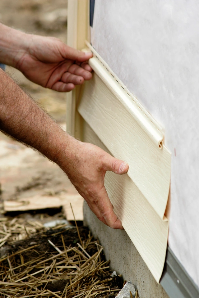 a pair of hands installing siding