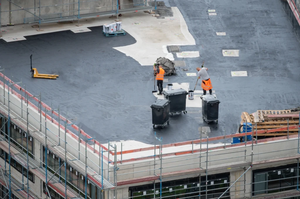 commercial roofing contractors work on installing new roof coating on flat roof