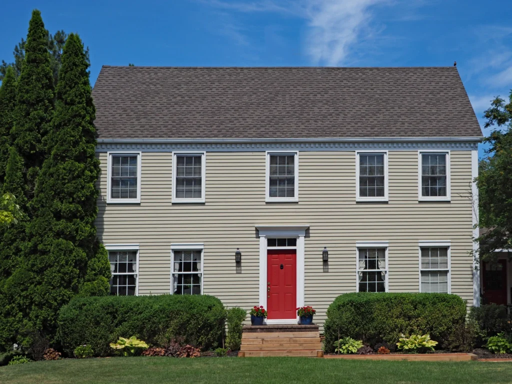 A beige two-story house with natural clay CertainTeed siding colors features a red front door, white trim, and six windows
