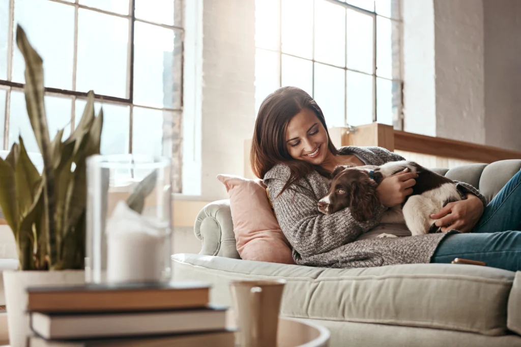 Happy young woman hold puppy on the couch in her hatboro home