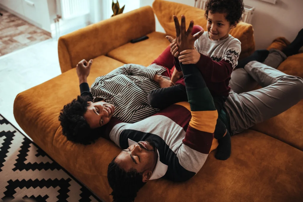 Dad plays with two children on couch