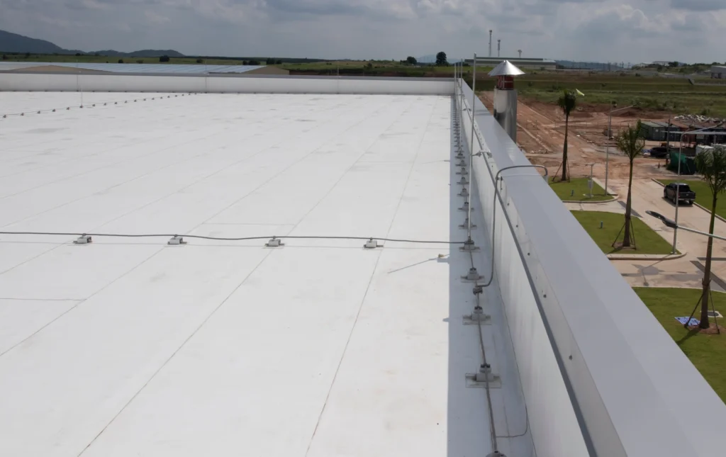 A large, flat, white roof with flat roof flashing stretches into the distance