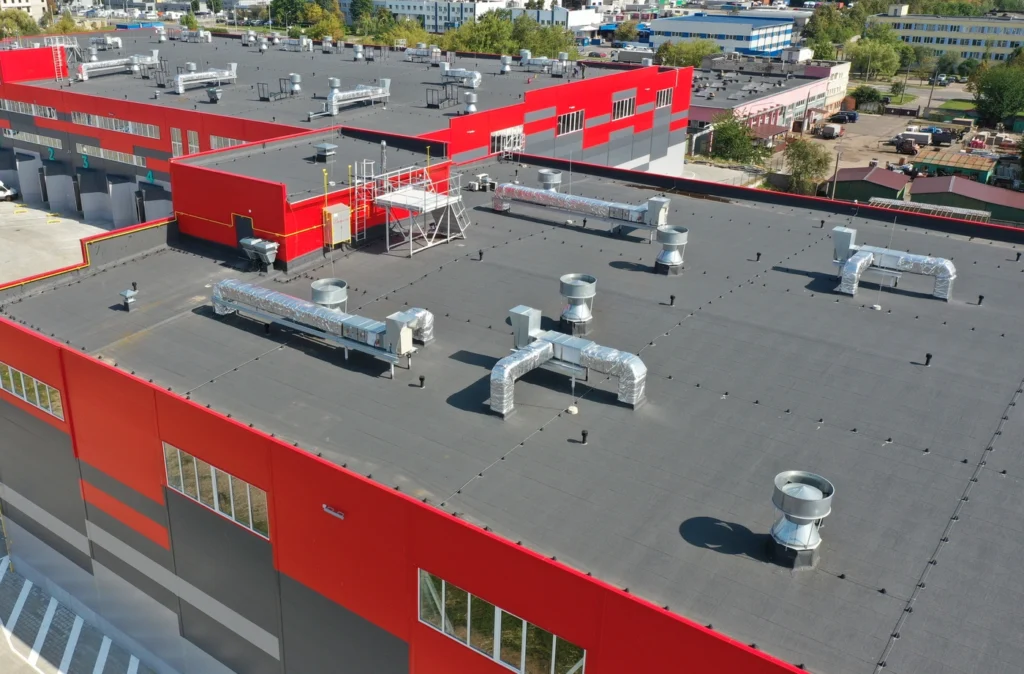 Aerial view of an industrial building with a flat black roof equipped with gutters for efficient drainage