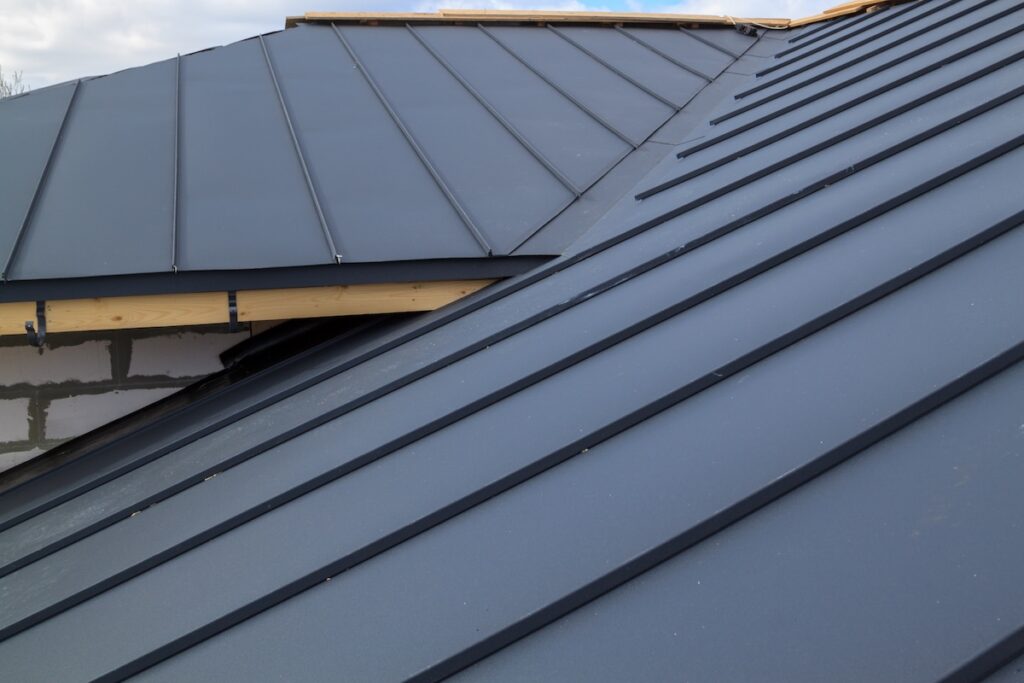 A close-up view of a sleek, black metal roof with standing seam panels.