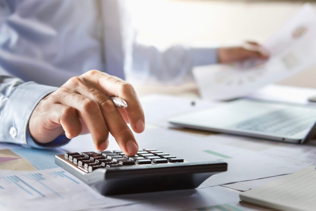 A person in business attire presses buttons on a calculator
