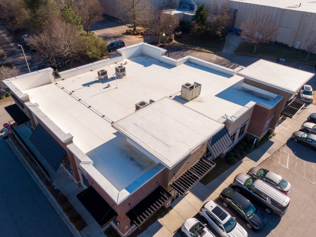 Aerial view of a commercial building with a flat white TPO roof