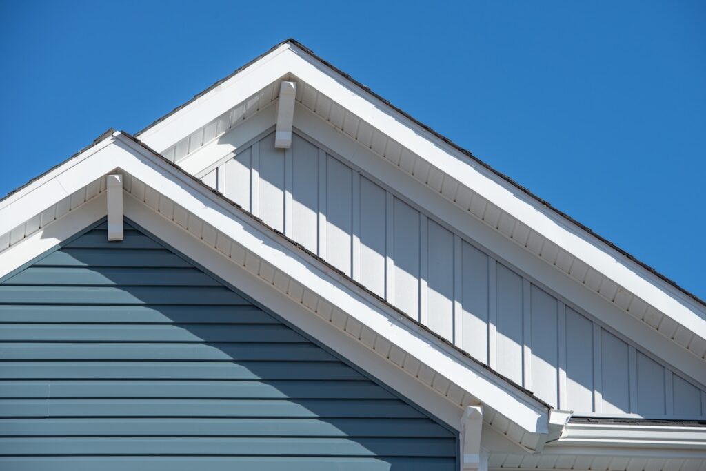 Close-up of two intersecting house gables with white trim, highlighting the fascia