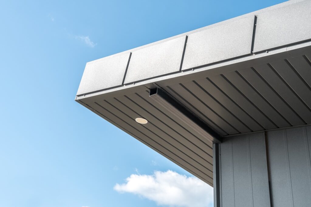 Close-up view of a modern building’s flat metal roof overhang with metal siding and soffit