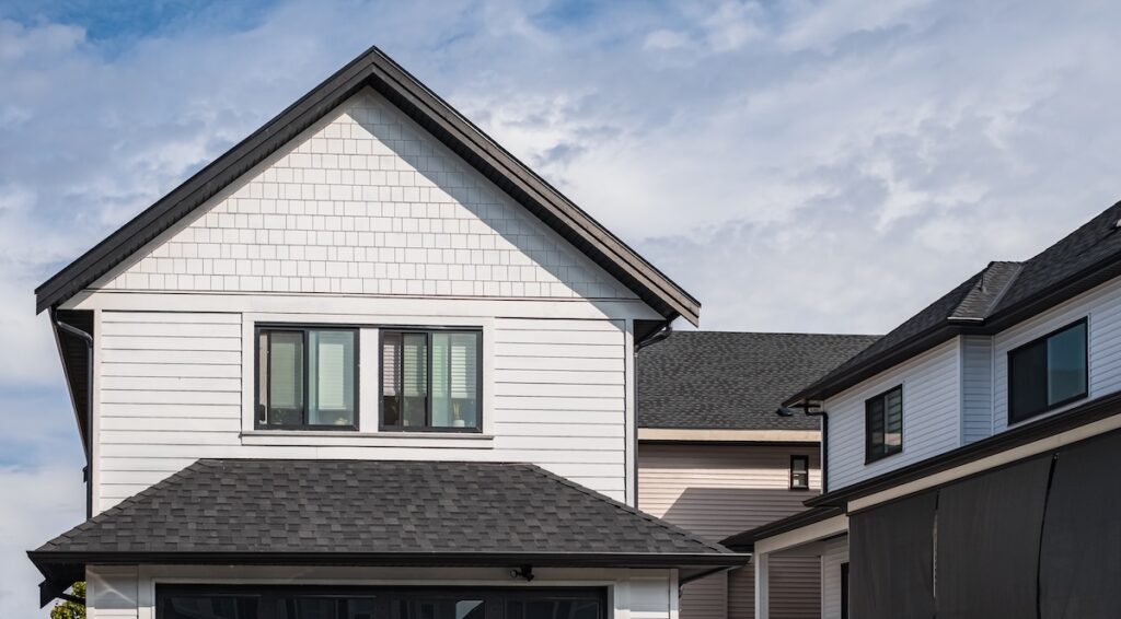 A modern two-story house with white siding, black trim, and a dark shingle roof 