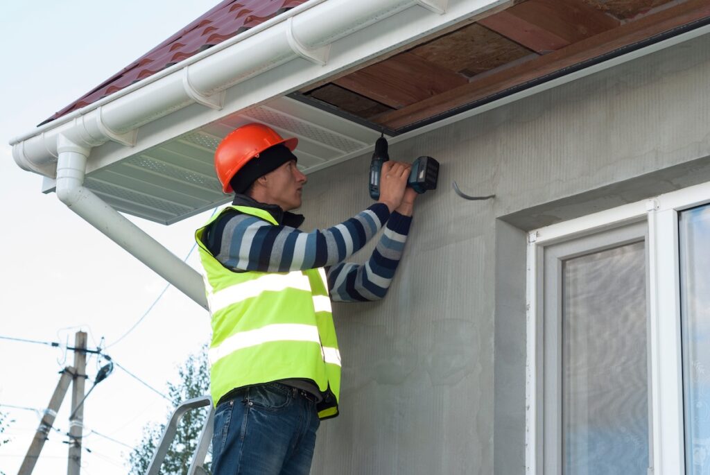 construction worker mounts a soffit on the roof eaves